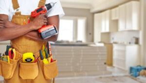 man in overalls holding must-have power tools, including a cordless drill